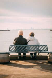 Elderly Couple Sitting on Bench in Seaside